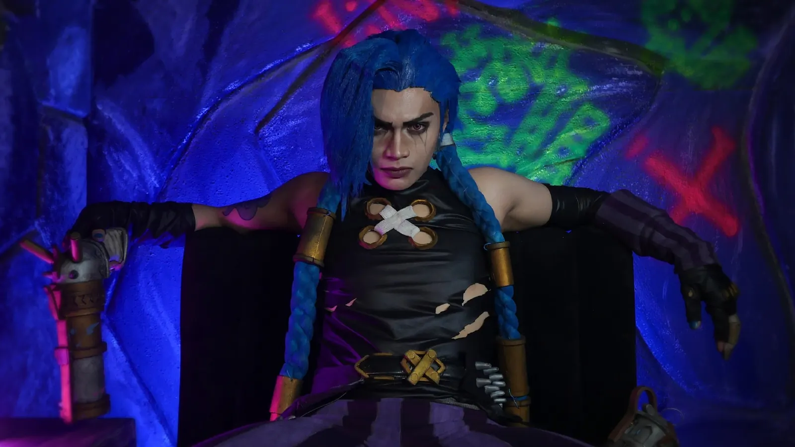 Jinx from Arcane cosplay seated on a styled throne set